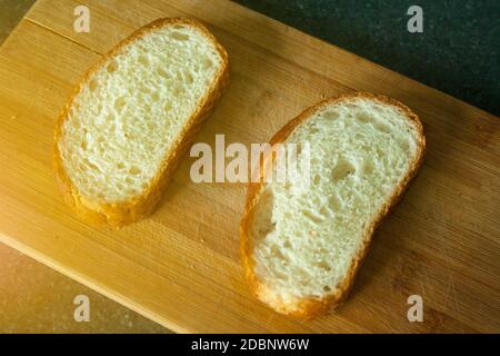 Tagliate due fette di pane sul tagliere Foto Stock