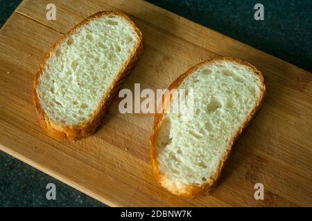 Tagliate due fette di pane sul tagliere Foto Stock