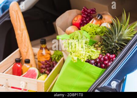 Servizio di alimentari che dà verdure fresche e frutta e cibo in borsa di stoffa verde e cestino di legno sulla vettura posteriore pronta consegna per inviare la donna cliente Foto Stock