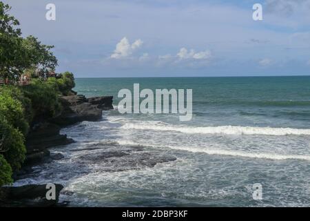 Costa dell'Oceano Indiano vicino al tempio Sacro Balinese Tanah Lot. Pura Batu Bolong sul bordo di una scogliera sulla costa con buco nella roccia. Luogo santo f Foto Stock