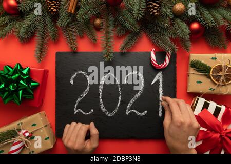 Un uomo scrive l'iscrizione 2021 su una tavoletta di granito nero in gesso. Foto Stock