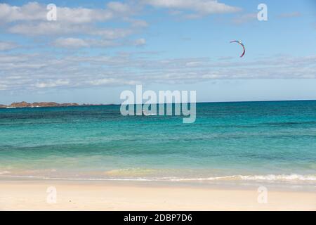 Kitesurfer sconosciuto surfing su un'acqua piatta azzurra dell'oceano Atlantico a Corralejo, Fuerteventura, isole Canarie, Spagna Foto Stock