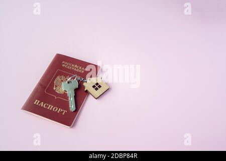 Russian International Passport e chiave con trinket casa su di esso su sfondo rosa primo piano su copia spazio. Immigrazione, emigrazione, cittadinanza Foto Stock