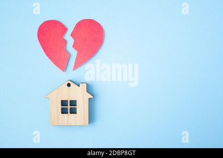 Divorzio, divisione della proprietà, povertà e nessun concetto di denaro. Casa di legno con cuore rotto su sfondo blu brillante. Ipoteca, affitto, realtor Foto Stock