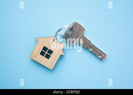 Disposizione portachiavi a forma di chiave e di casa su sfondo blu. Vista dall'alto, disposizione piatta. Immobiliare, concetto di assicurazione, ipoteca, comprare vendere casa, realtor co Foto Stock