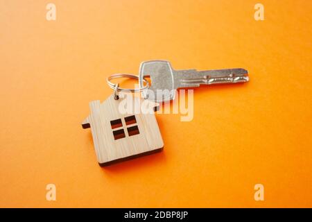 Disposizione portachiavi a forma di chiave e di casa su sfondo arancione. Vista dall'alto, disposizione piatta. Immobiliare, concetto di assicurazione, ipoteca, comprare vendere casa, realtor Foto Stock
