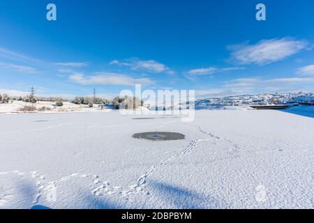 Lago artificiale ghiacciato in un giorno di inverni luminosi e croccanti Foto Stock