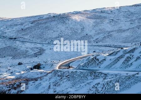 Strada tortuosa che attraversa un paesaggio invernale freddo e innevato Foto Stock