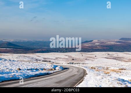 Strada tortuosa che attraversa un paesaggio invernale freddo e innevato Foto Stock