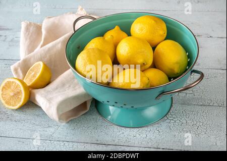 Limoni freschi in colino blu. Sfondo di legno Foto Stock