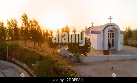 Vista aerea del tramonto e simbolo bianco dipinta cappella moderna arco di Agia Triada, Protaras, Famagosta, Cipro dall'alto. Vista dall'alto del turista Foto Stock