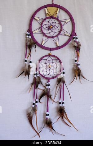 Dreamcatcher rosso nero e viola con pipistrello in pelle di piume perline e corde, appesi su sfondo bianco. Foto Stock