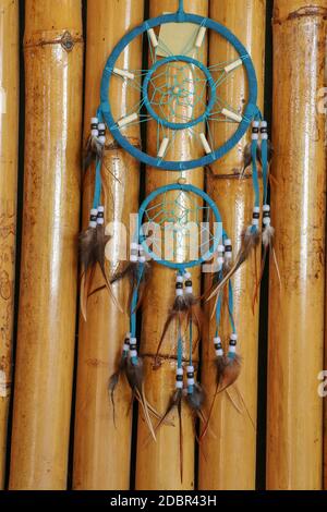 Blue Dreamcatcher con piume e perline isolate su sfondo di bambù. Foto Stock