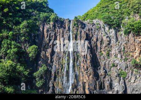 Rockface con cascata Niagara a Reunion in isola francese l'oceano indiano in una giornata soleggiata con cielo blu Foto Stock