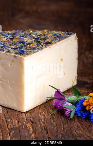 formaggio di montagna con fiori su legno Foto Stock