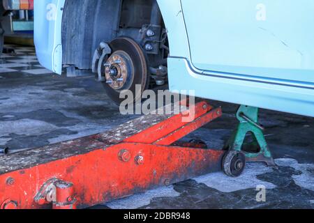 Sostituzione delle ruote su un'auto, il martinetto mantiene la carrozzeria in posizione sollevata. Foto Stock