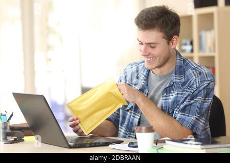 Felice uomo imprenditore apre busta seduta su una scrivania in ufficio Foto Stock