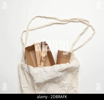 borsa in tessuto bianco e stoviglie monouso di carta marrone artigianale su sfondo bianco. Vista dall'alto, concetto di rifiuto della plastica, zero sprechi Foto Stock