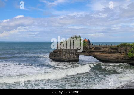Le onde arrivano a una scogliera sotto il tempio di Batu Bolong. Tanah Lot tempio. Enorme buco nella roccia sotto il tempio pura Batu Bolong. Tempio indù sul BE Foto Stock