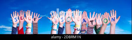 Mani dei bambini che tiene l'auto-isolamento colorato della parola inglese. Cielo blu come sfondo Foto Stock