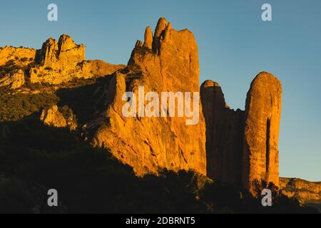 Montagne dei Mallos de Riglos, pareti verticali di roccia al tramonto, un luogo famoso per l'arrampicata vicino al fiume Gallego, nei prePirenei, Huesca Prov Foto Stock