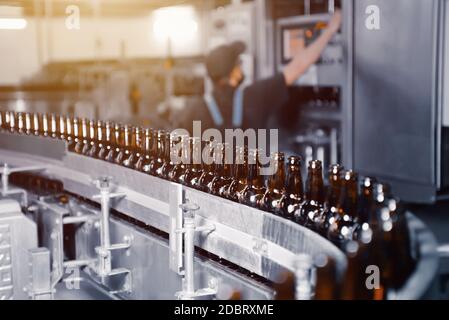 Bottiglie di birra in vetro di colore marrone sulla linea di trasporto di imbottigliamento della birra da vicino Foto Stock