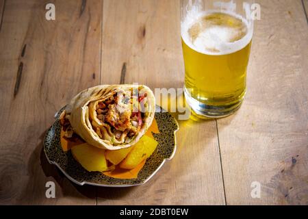 Carne stufata con verdure avvolte in pasta giace su un piatto e un bicchiere di birra leggera Foto Stock