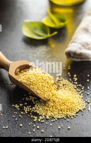 Couscous giallo secco in paletta di legno. Foto Stock