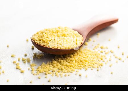 Asciugare il couscous giallo in un cucchiaio di legno. Foto Stock