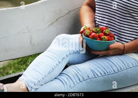 Donna che tiene fragole fresche . Sfondo estivo con relax su panca . Foto Stock