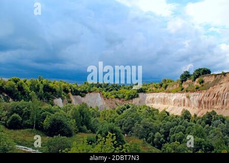 Cava di Cretaceo. Paesaggio con scogliere sabbiose e tuono cielo tempesta. Cretaceo buca. Scogliere di sabbia con foresta a piedi. Montagne sabbiose. lan celeste Foto Stock