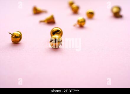 Piccole campane dorate su sfondo rosa, fuoco selettivo sul primo piano Foto Stock