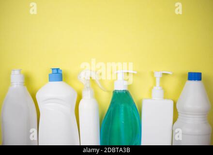 Una serie di prodotti per la pulizia su sfondo giallo. Prodotti chimici per uso domestico. Un set di prodotti per la pulizia. Detergenti in bottiglie bianche Foto Stock
