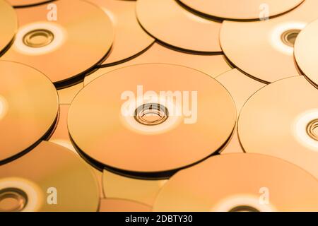 CD e DVD in tonalità dorata come sfondo. Messa a fuoco morbida. Foto Stock