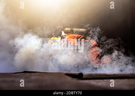 Vigili del fuoco controllare e salvare un uomo in costruzione con fumo dal fuoco all'interno. Misure di sicurezza per vigili del fuoco contro incidenti e concetto di servizio pubblico. Foto Stock