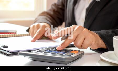 Primo piano di uomini d'affari o contabili che tengono una penna e che premono sulla calcolatrice per calcolare le informazioni di affari, i documenti contabili, il commercio Foto Stock