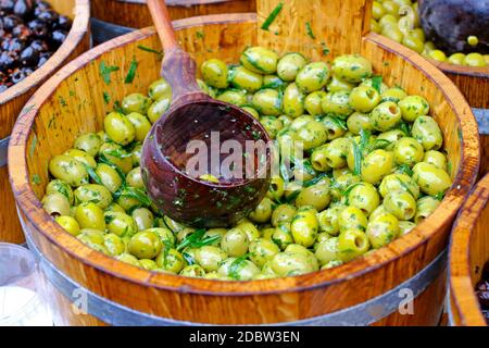 Olive verdi in secchio di legno venduto sul mercato Foto Stock