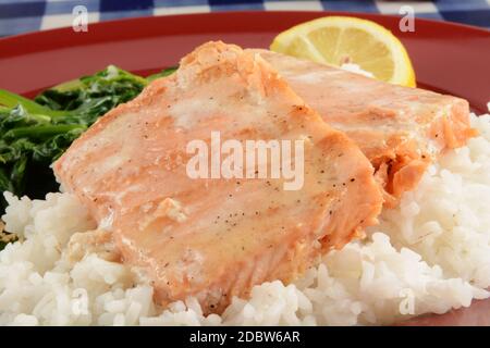 Bistecche di salmone grigliate servite su un letto di riso con spinaci Foto Stock