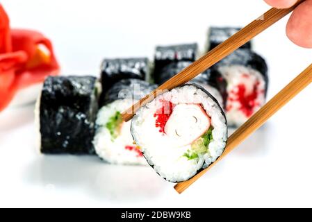 primo piano di bacchette che prendono parte al sushi roll on il ristorante da tavolo / mangiare sushi roll utilizzando bastoncini Foto Stock