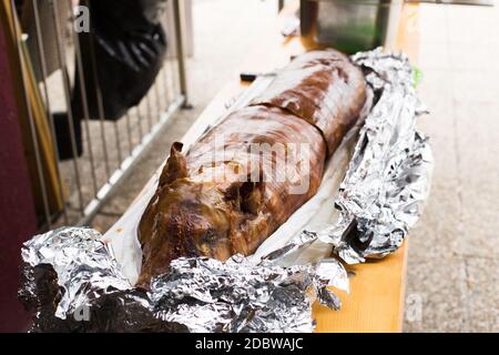 Maialino alla griglia / suzione, con la pelle ancora su di esso avvolto in lamina di alluminio. Foto Stock