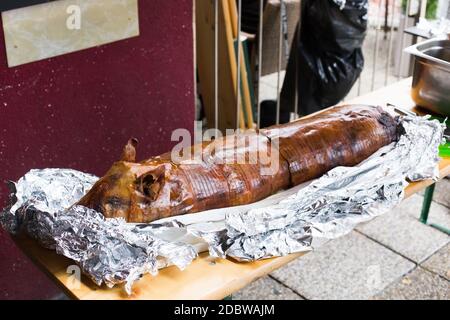 Maialino alla griglia / suzione, con la pelle ancora su di esso avvolto in lamina di alluminio. Foto Stock