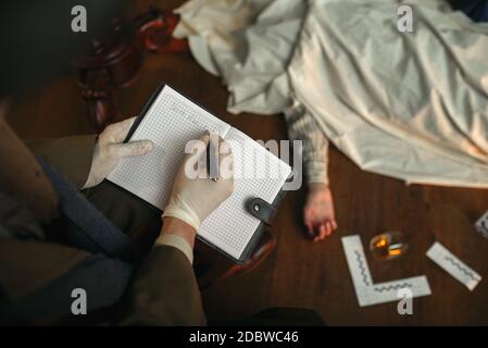 Il detective maschile con sigaro scrive in notebook, vittima sotto il capo alla scena del crimine, stile retrò. Indagine penale, ispettore sta lavorando su un Foto Stock