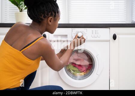 Persona mano impostazione lavatrice per vestiti lavanderia Foto Stock
