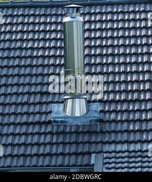 Un camino in acciaio inossidabile coperto nelle tegole di fondo del tetto. Spazio di copia per il testo. Foto Stock