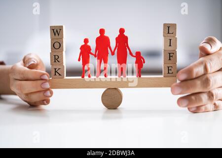 Coppia felice la protezione di equilibrio tra lavoro e vita familiare e carta ritagliata su altalena Foto Stock