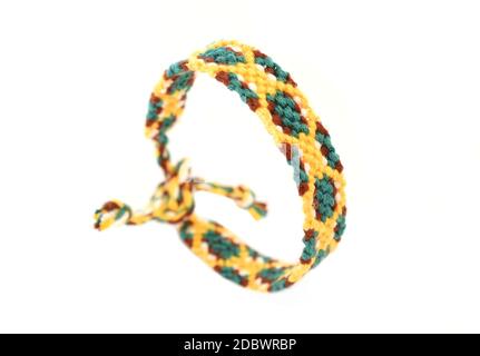 Fuoco selettivo del bracciale di amicizia tessuto fai da te fatto a mano di ricamo filo luminoso con nodi isolati su sfondo bianco. Boho Foto Stock