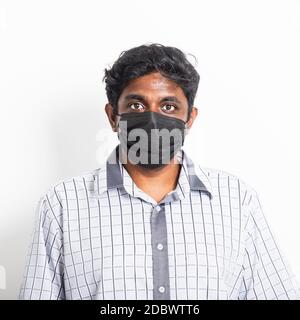 Asian felice ritratto giovane uomo nero che indossa maschera protettiva da virus coronavirus epidemia o inquinamento atmosferico cercando fotocamera, studio di ripresa isolato Foto Stock