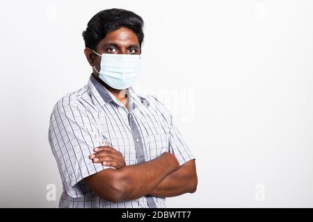 Closeup Asian bel uomo nero indossando chirurgico igienico maschera di tessuto protettivo contro il coronavirus e braccio in piedi incrociati, studio girato isolato Foto Stock