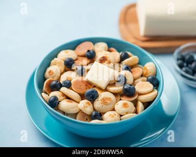 Cibo alla moda - cereali pancake. Un mucchio di mini frittelle di cereali in boul su sfondo blu. Spazio di copia per testo o disegno Foto Stock