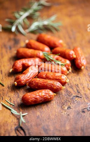 Mini salsicce di salame su tavolo di legno. Foto Stock